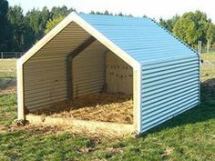 a small shed with hay in it on the grass