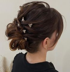 a woman with her hair in a low bun and some small flowers on the side