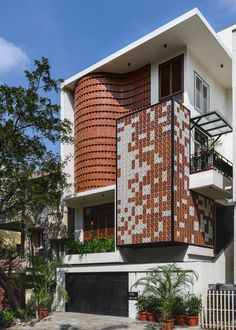 a building with red and white tiles on the side, surrounded by plants and trees