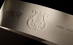 a close up of a business card on a black surface with white paper and silver foil