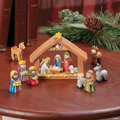 a nativity scene with figurines on a table next to books and pine cones