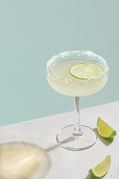 a margarita sitting on top of a table next to limes