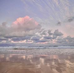 the sky is filled with clouds and reflecting in the wet sand at the beach on a cloudy day