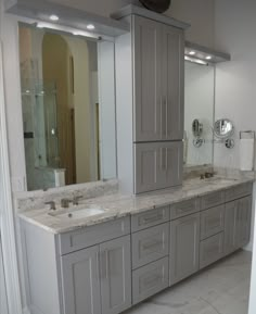 a large bathroom with two sinks and mirrors on the wall, along with other cabinets