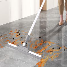 a woman using a mop to clean the floor with orange stains on it and her feet