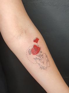 a woman's arm with a red heart and flower tattoo on the left forearm