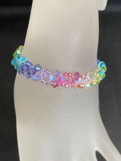 a white mannequin wearing a bracelet with multicolored beads