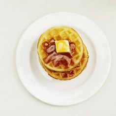 two waffles on a white plate topped with syrup and butter