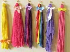 four different colored tassels hanging on a wall with bows and ribbons attached to them