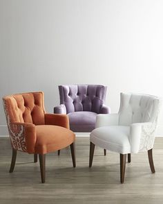 four different colored chairs sitting on top of a hard wood floor next to a white wall