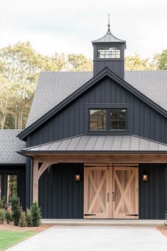 a black barn with two doors and a clock tower