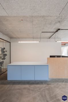 an empty office space with blue cabinets and white walls, in the middle of a concrete floor