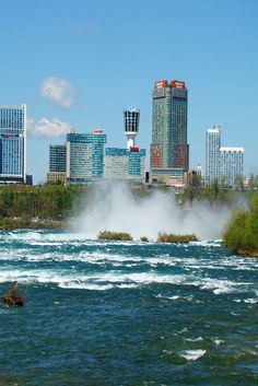 a river with steam rising from it and buildings in the background