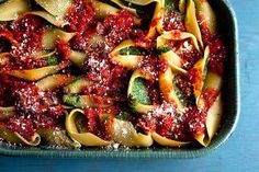 pasta with sauce and spinach in a pan on a blue table top, ready to be eaten