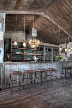 an old bar with stools and lights hanging from the ceiling