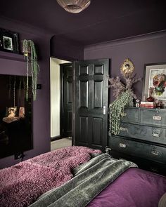 a bedroom with purple walls and black furniture