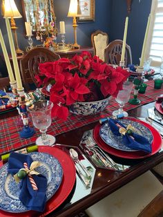 the table is set for christmas dinner with poinsettis and other holiday decorations