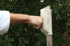 a person holding onto a piece of cloth with their hand on the pole and trees in the background