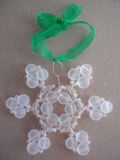 a snowflake ornament hanging from a green ribbon on top of a table