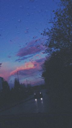 the sky is purple and blue at night with raindrops on the street below