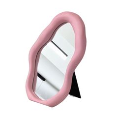 a pink and white mirror sitting on top of a black stand in front of a white wall