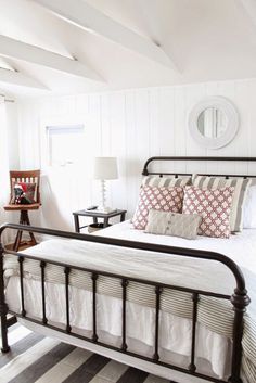 a bed sitting in a bedroom next to a window with white walls and wooden floors