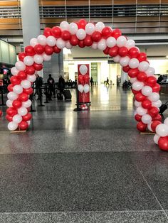 red, white and blue balloons are arranged in an arch on the floor at an airport