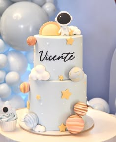 a cake with an astronaut theme on it and balloons in the background for a space themed birthday party