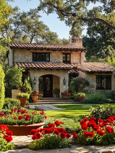 a beautiful house with red flowers in the front yard and large potted plants on the lawn