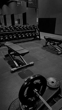 an empty gym with rows of benches and dumbbells on the floor in black and white