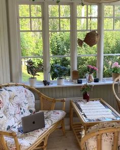 two wicker chairs and a table in front of a window with flowers on it