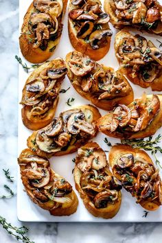 an assortment of appetizers on a white platter with herbs and rosemary sprigs