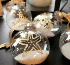 three glass ornaments with starfishs and snowflakes on them sitting on a table