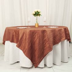 the table is set with two wine glasses and a flower vase on top of it