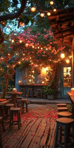 an outdoor dining area with tables and stools covered in rose petals, lit by lanterns