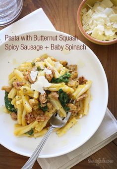 pasta with butternut squash, spicy sausage and baby spinach on a white plate