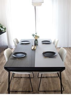 a dining room table with plates and place settings on it in front of a window