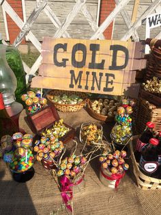 a table topped with lots of bottles and baskets filled with candy next to a sign that says gold mine