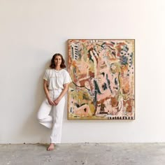 a woman leaning against a wall next to a painting