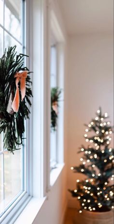 a wreath hanging on the side of a window next to a christmas tree with lights