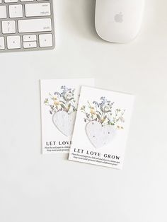 two cards sitting on top of a white desk next to a computer keyboard and mouse