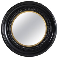 a black and gold circular mirror with an ornate design on the rim, in front of a white background