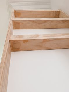 the bottom part of a set of stairs made out of plywood and white paint