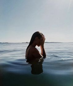 a woman is floating in the water with her head above her chin and hands to her face