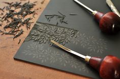 a pair of scissors sitting on top of a cutting board next to some tea leaves