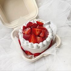 a white cake with strawberries in it on a plate next to a plastic container