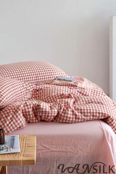 an unmade bed with a red and white checkered comforter on the bottom