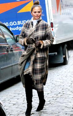 a woman is walking down the street in her coat