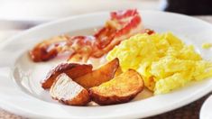 a white plate topped with eggs, bacon and potatoes