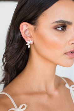 a woman wearing earrings with bows on her shoulder